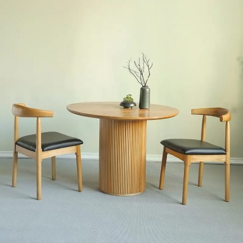 Bàn ăn tròn gỗ tự nhiên và bốn ghế bọc da màu trắng đặt trong phòng ăn hiện đại