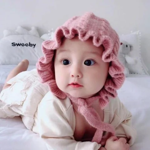 Bé gái mặc váy trắng ngồi trên bãi cỏ